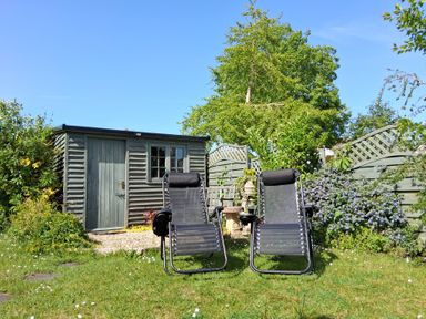 A garden with deck chairs and a shed at Crooked Well in Timsbury, Nr Bath