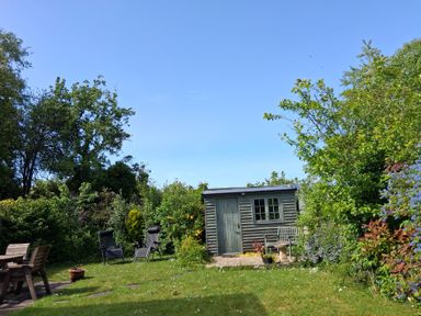 A garden with a shed and seating area at Crooked Well Timsbury, Nr Bath