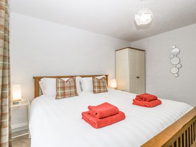 A bedroom with a double bed two plaid pillows red towels a wardrobe and a circular mirror arrangement at Orchard House in Risbury near Leominster