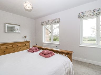 A bedroom with a wooden dresser and bed with folded towels on the bed at Orchard House Risbury near Leominster
