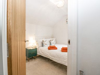 A bedroom with a bed with white linens and orange towels a bedside table with a lamp and pillows at Orchard House Risbury near Leominster