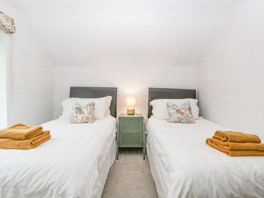 A bedroom with two single beds white bedding a small green nightstand and a lamp at Orchard House in Risbury near Leominster