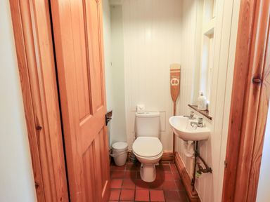 A small bathroom with a toilet sink wooden door and wooden oar on the wall at St Peters Cottage in Milnthorpe