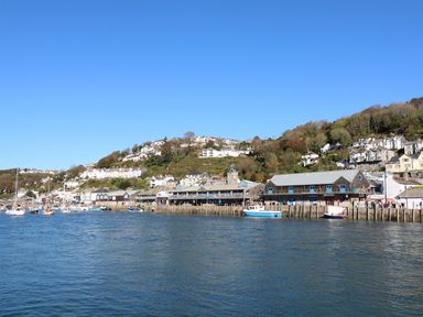A harbor with boats and buildings along the waterfront under a clear blue sky at Blue Sky Cottage Rosecraddoc Lodge near Liskeard