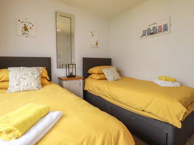 A bedroom with two single beds with yellow bedding and seagull pillows at Blue Sky Cottage Rosecraddoc Lodge near Liskeard