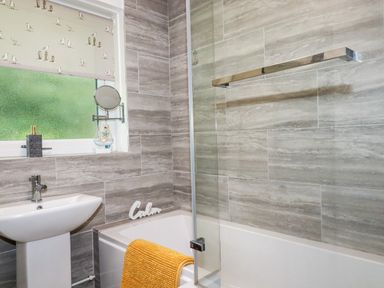 A bathroom with a sink bathtub and window with patterned blind at Blue Sky Cottage Rosecraddoc Lodge near Liskeard