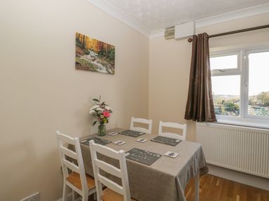A dining room with a table covered by a cloth and four chairs near a window with a curtain at The Annex in Drybrook