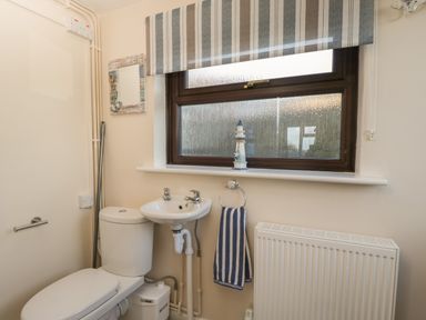 A bathroom with a toilet sink striped towel window and radiator at The Annex in Drybrook