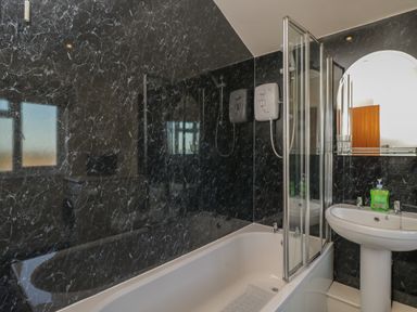 A bathroom with a bathtub shower sink mirror and soap dispenser at The Annex in Drybrook