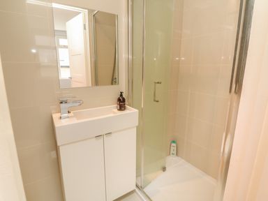 A bathroom with a sink and cabinet next to a glass shower enclosure at The Old Coach House in Braunton