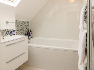 A bathroom with a bathtub sink vanity with toiletries and towels at The Old Coach House in Braunton