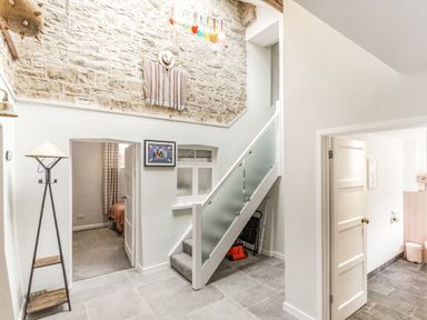 A hallway with stairs and doorways leading to other rooms and a stone wall at The Old Coach House in Braunton