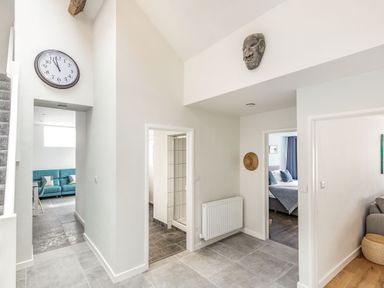 A hallway with a wall clock and two doorways showing a bathroom and a bedroom at The Old Coach House in Braunton