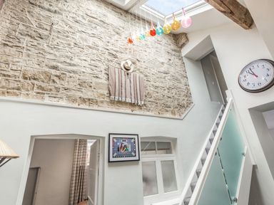 An interior hallway with stairs a large clock a framed picture and a stone wall at The Old Coach House in Braunton