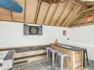 A game room with a dartboard a bar counter with stools and a foosball table at The Old Coach House in Braunton