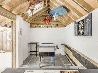 A game room with a foosball table a dartboard wooden walls and ceiling at The Old Coach House in Braunton
