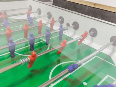 A foosball table with red and blue players on rods at The Old Coach House in Braunton