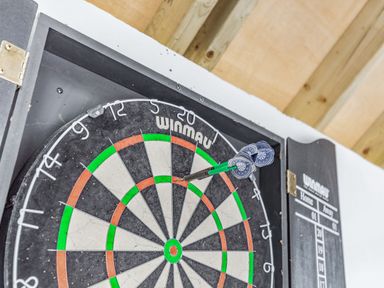 A dartboard with three darts in the bullseye area mounted on a wall