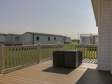 A deck with a table and chairs outside mobile homes at Daisy Lodge in Cayton Bay near Cayton