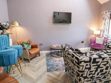 A living room with a sofa, armchairs, and a television at Pengwern in Llanrwst