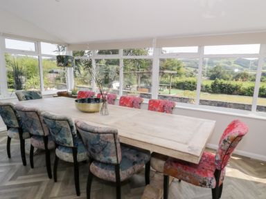 A dining room with a large table and colorful chairs at Pengwern in Llanrwst