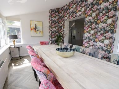 A dining room with a large table and floral wallpaper at Pengwern in Llanrwst