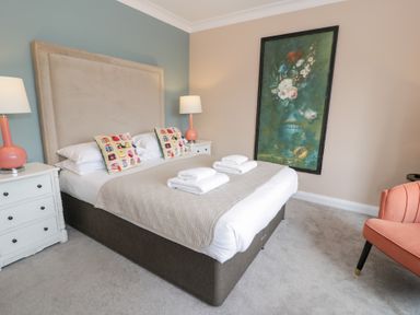A bedroom with a bed, bedside tables, lamps, and a painting at Pengwern in Llanrwst