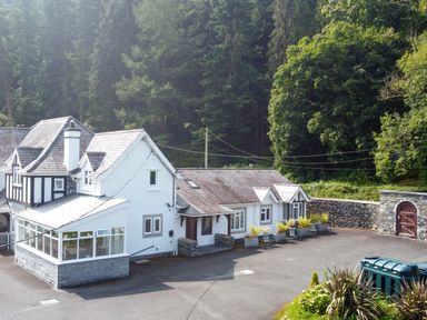 A house with a conservatory surrounded by trees at Pengwern in Llanrwst