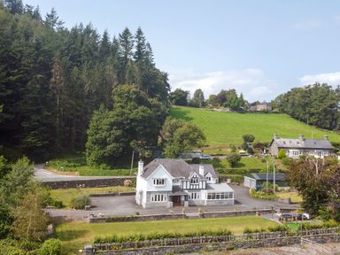 A house with garden and trees in the background at Pengwern Llanrwst