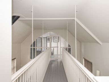 A narrow hallway with white railings and a glass door at the end at St Mary's Chapel in West Lulworth