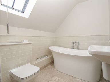 A bathroom with a bathtub toilet and sink under a skylight at St Mary's Chapel in West Lulworth
