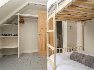 A bedroom with a bunk bed wooden closet shelves and a wooden door at St Mary's Chapel in West Lulworth