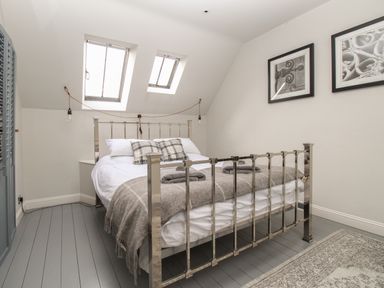 A bedroom with a metal framed bed two skylight windows and framed pictures on the wall at St Mary's Chapel in West Lulworth