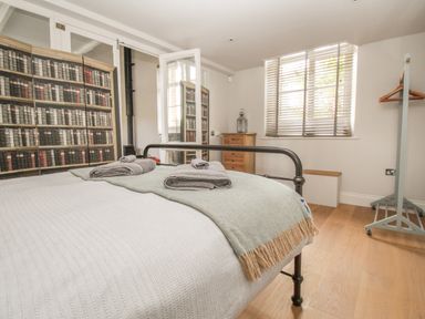 A bedroom with a metal bed frame with towels on the bed a wooden chest of drawers and a clothes rack at St Marys Chapel in West Lulworth