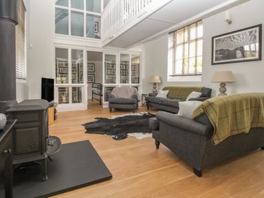 A living room with gray sofas and a black wood stove at St Marys Chapel in West Lulworth