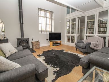 A living room with sofas tv wood burner and animal hide rug at St Marys Chapel in West Lulworth
