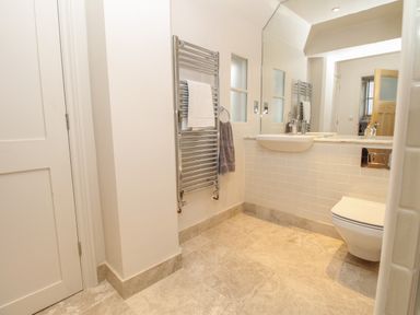 A bathroom with a wall-mounted sink toilet heated towel rail and mirror at St Mary's Chapel in West Lulworth