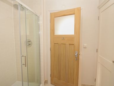 A bathroom with a glass shower enclosure and a wooden door at St Mary's Chapel in West Lulworth
