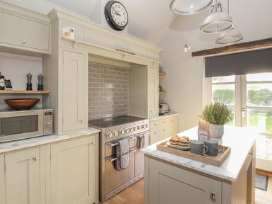 A kitchen with stove microwave cabinets and island with mugs and plant at St Marys Chapel in West Lulworth