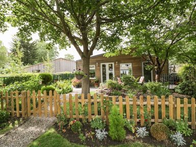 A garden with a wooden fence trees plants and a wooden building at The Garden House in Upper Quinton near Lower Quinton