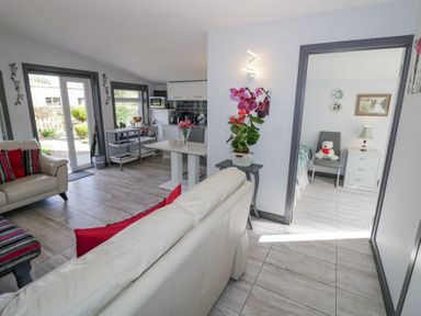 A living room with white sofas and red cushions next to a dining table and kitchen at The Garden House Upper Quinton near Lower Quinton