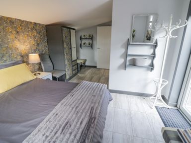 A bedroom with a bed a nightstand and lamp a chair wardrobe and a coat rack at The Garden House Upper Quinton near Lower Quinton