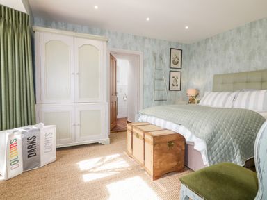 A bedroom with a bed a wooden chest a white wardrobe and a laundry bag at Louvain Cadgwith near Ruan Minor