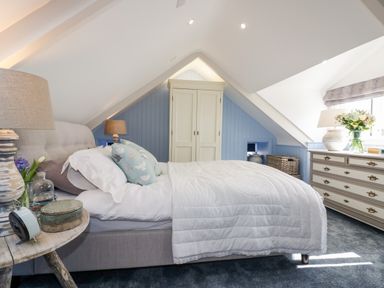 A bedroom with a bed a wardrobe a dresser and a side table at Louvain in Cadgwith near Ruan Minor