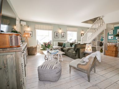 A living room with a sofa armchair ottoman coffee table and stairs at Louvain in Cadgwith near Ruan Minor