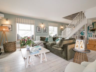 A living room with green sofa and wooden coffee table near staircase at Louvain in Cadgwith near Ruan Minor