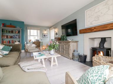 A living room with a fireplace sofa armchairs coffee table and bookshelf at Louvain in Cadgwith near Ruan Minor