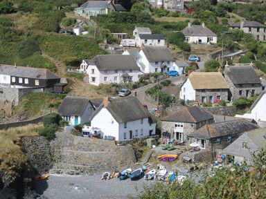 A coastal village with boats on a pebble beach and stone houses with thatched roofs at Louvain in Cadgwith near Ruan Minor