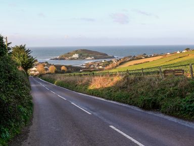 A road leading to a coastal village with green fields and an island in the sea at 2 The Bay in Bigbury