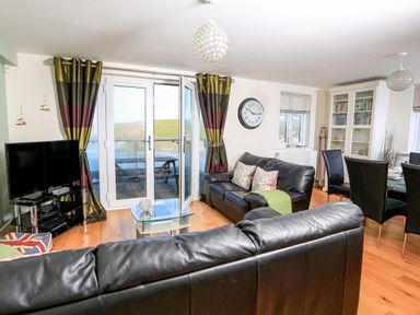 A living room with leather sofas a glass coffee table a television and dining area at 2 The Bay in Bigbury